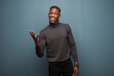 Genç Afro-Amerikan siyahi adam mutlu, şaşırmış ve neşeli hissediyor. Pozitif bir tavırla gülümsüyor. Bir çözüm ya da grunge duvarına karşı bir fikir buluyor.