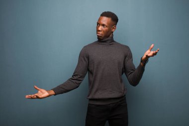 Genç Afro-Amerikan siyahi adam aptal, deli, kafası karışık, şaşkın bir ifadeyle omuz silkiyor. Sinirli ve cahil hissediyor.