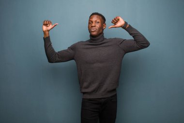Genç Afro-Amerikan siyahi adam gururlu, kibirli ve kendinden emin, tatmin olmuş ve başarılı görünüyor.
