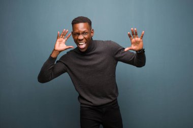 Genç Afro-Amerikan siyahi adam panik ya da öfke içinde bağırıyor, şok olmuş, korkmuş ya da öfkeli, elleri grunge duvarının yanında.