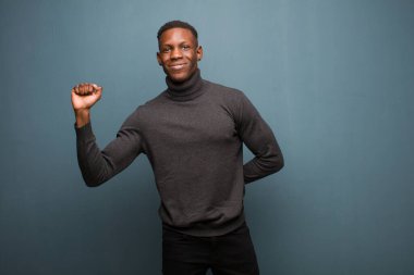 Genç Afrikalı Amerikalı siyah adam ciddi, güçlü ve isyankar hissediyor, yumruğunu kaldırıyor, protesto ediyor ya da grunge duvarına karşı devrim için savaşıyor.