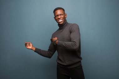 Genç Afro-Amerikan siyahi adam şok olmuş ve şaşırmış hissediyor. Kenardaki kopya alanını işaret ediyor. Ağzı açık, hayret verici bir şekilde grunge duvarına bakıyor.