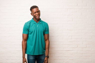 Genç Afrikalı Amerikalı siyah adam korkmuş ve şok olmuş hissediyor, ağzı açık tuğla duvara karşı şaşkınlık içinde.