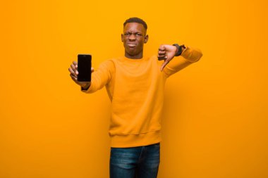 Genç Afro-Amerikan siyah adam turuncu duvara karşı akıllı bir telefonla