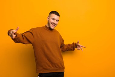 Genç yakışıklı adam mutlu, kibirli, gururlu ve kendinden memnun görünüyor, düz arkaplan karşısında kendini bir numara gibi hissediyor.