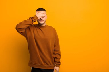 Genç ve yakışıklı bir adam gözlerini kapatıyor. Korkmuş ya da endişeli hissediyor, merak ediyor ya da kör bir şekilde düz arkaplana karşı bir sürpriz bekliyor.