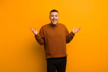 Genç yakışıklı adam mutlu, heyecanlı, şaşırmış ya da şaşırmış hissediyor, gülümsüyor ve şaşırıyor.