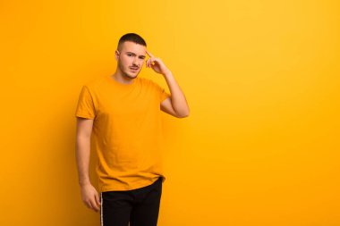 Genç yakışıklı adam şaşkın ve şaşkın hissediyor. Deli, deli ya da düz arkaplan karşısında aklını kaçırmış olduğunu gösteriyor.