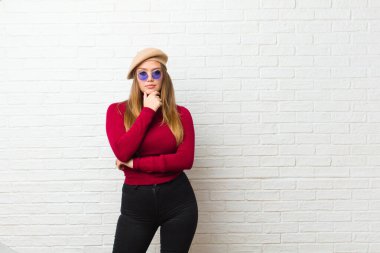 Genç sanatçı kadın ciddi, düşünceli ve güvensiz görünüyor, bir kolu çapraz ve çene üzerinde, seçenekleri tartıyor