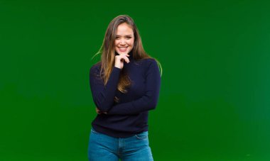 Genç, güzel bir kadın, kafası karışmış ya da şüpheye düşmüş, bir fikre odaklanmış, çok düşünüyor, yeşil arka planda uzayı kopyalamak istiyor.