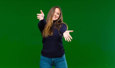 Genç, güzel bir kadın neşeyle gülümsüyor sıcak, dostça, sevgi dolu bir kucaklama yapıyor, yeşil arka planda mutlu ve sevimli hissediyor.