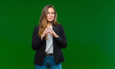 Genç, güzel bir kadın kötü bir plan yaparken gururlu, yaramaz ve kibirli hissediyor ya da yeşil arka plana karşı bir numara düşünüyor.