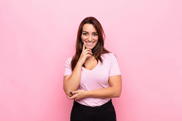 若い可愛い女性は ピンクの壁とオプションを比較し 疑問や質問を あごに手で幸せと笑顔を見て — ストック写真