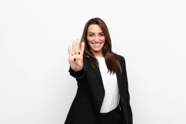 Genç ve güzel iş kadını gülümsüyor ve arkadaş canlısı görünüyor. Elleri önde, beyaz duvara doğru geri sayıyor.