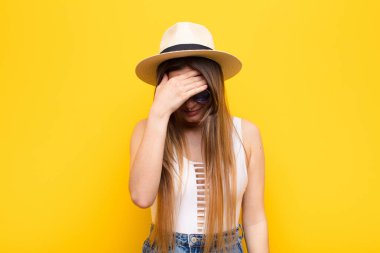 Genç, güzel bir kadın stresli, utanmış ya da üzgün görünüyor. Baş ağrısı var, yüzü elle kapatılmış.