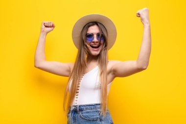 Genç ve güzel bir kadın muzaffer bir şekilde bağırıyor. Heyecanlı, mutlu ve şaşırmış görünüyor. Kutlama yapıyor.