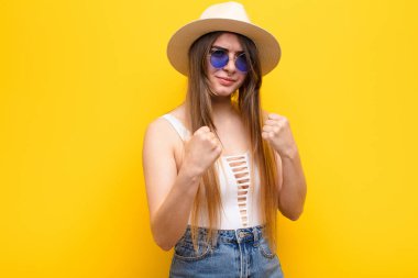 Genç ve güzel bir kadın kendinden emin, sinirli, güçlü ve agresif görünüyor. Yumrukları boks pozisyonunda dövüşmeye hazır.