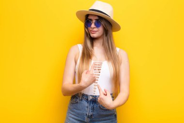 Genç ve güzel bir kadın, şaşkın ve şaşkın bir bakışla kendini işaret ediyor, seçildiğine şaşırmış ve şaşırmış.