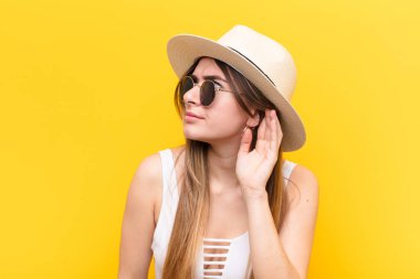 Genç ve güzel bir kadın ciddi ve meraklı görünüyor, dinliyor, gizli bir konuşma veya dedikodu duymaya çalışıyor, kulak misafiri oluyor.