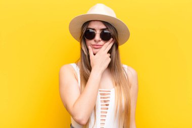 Genç ve güzel bir kadın ciddi, düşünceli ve güvensiz görünüyor. Bir kolu çapraz, eli çenesinde, seçenekleri değerlendiriyor.