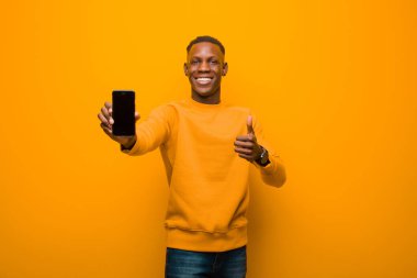 Genç Afro-Amerikan siyah adam turuncu duvara karşı akıllı bir telefonla