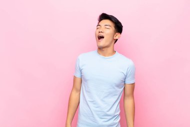 Genç Çinli adam öfkeyle bağırıyor, agresif bir şekilde bağırıyor, stresli ve sinirli görünüyor.