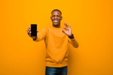Genç Afro-Amerikan siyah adam turuncu duvara karşı akıllı bir telefonla
