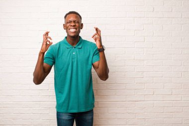 Genç Afrikalı Amerikalı siyahi adam gergin ve umutlu. Dua ediyor ve tuğla duvara karşı iyi şanslar diliyor.