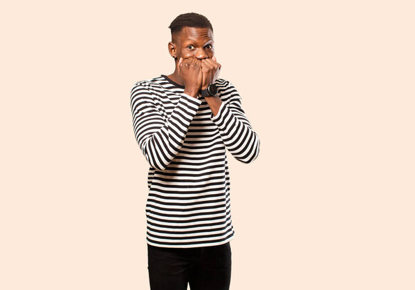 Young african american black man looking worried, anxious, stressed and afraid, biting fingernails and looking to lateral copy space against beige wall