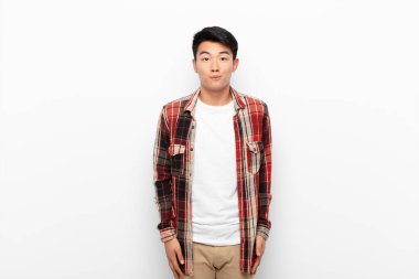 Genç Çinli bir adam üzgün ve stresli. Kötü bir sürpriz yüzünden üzgün. Renk duvarına karşı olumsuz ve endişeli bir bakışla.