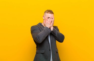 Sarışın genç işadamı korkmuş ya da utanmış hissediyor, gözleri yarı kapalı ya da elleri kapalı gözetliyor.