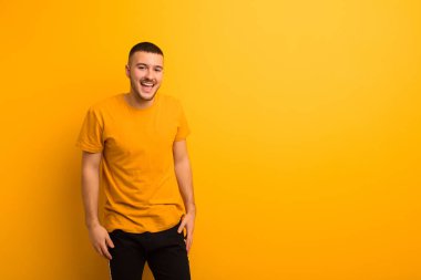 Genç, yakışıklı, büyük, dost canlısı, kaygısız bir gülümsemesi olan, pozitif görünen, rahat ve mutlu görünen, düz arka planda takılan bir adam.