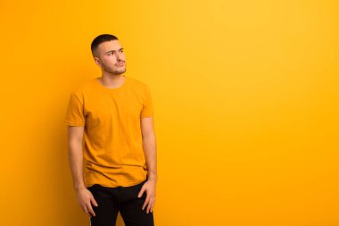 Kafası karışmış, kafası karışmış, bir sorunu çözmeye çalışan ya da düz arkaplan dışında düşünen genç yakışıklı bir adam.