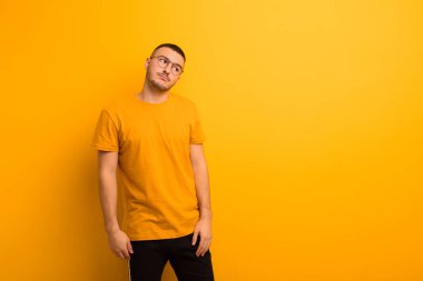 Genç yakışıklı adam merak ediyor, mutlu düşünceler ve fikirler düşünüyor, hayal kuruyor, düz arkaplana uzayı kopyalamaya çalışıyor.