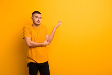 Genç ve yakışıklı bir adam kafası karışık ve bilgisiz, şüpheli bir açıklamayı merak ediyor ya da düz arkaplan hakkında düşünüyor.