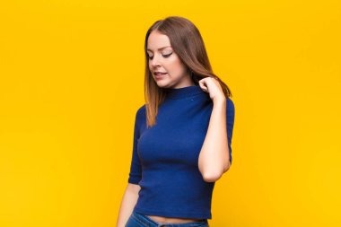 Genç kızıl saçlı kadın stresli, endişeli, yorgun ve hayal kırıklığına uğramış, gömleğini çekmiş, düz duvara karşı sorunlu görünüyor.