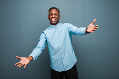 Genç Afrikalı Amerikalı siyah adam neşeyle gülümsüyor sıcak, dostça, sevgi dolu bir kucaklama, mutlu ve sevimli hissediyor.