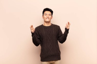 Genç Çinli adam endişeyle şans diliyor ve duvarlara karşı endişeli bakışlarıyla iyi şanslar diliyor.