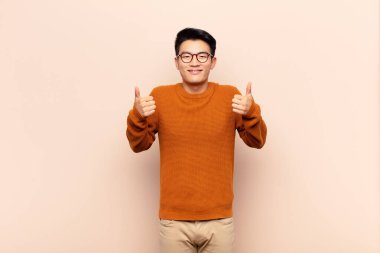 Genç Çinli adam mutlu, pozitif, kendine güvenen ve başarılı bir şekilde gülümsüyor.