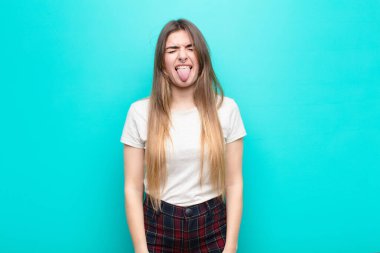 Genç, güzel bir kadın, tiksinmiş ve rahatsız olmuş hissediyor. Dilini dışarı çıkarıyor. Çirkin ve iğrenç bir şeyi mavi duvara yaslıyor.