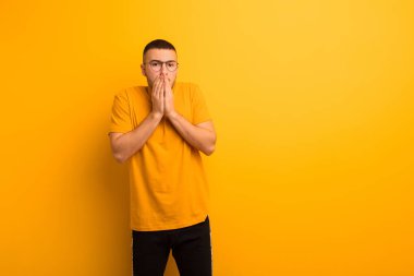 Genç yakışıklı adam endişeli, üzgün ve korkmuş hissediyor, elleriyle ağzını kapatıyor, endişeli görünüyor ve düz arkaplan karşısında berbat durumda.
