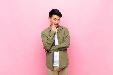 Genç Çinli adam sana göz kulak oluyor, güvenmiyor, izliyor ve düz renkli duvarlara karşı tetikte oluyor.