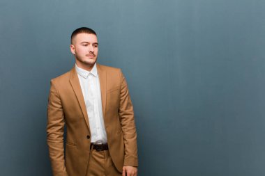 Genç yakışıklı adam üzgün, üzgün ya da kızgın ve olumsuz bir tavır takınıyor, düz duvara karşı anlaşmazlık içinde.