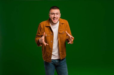 Genç yakışıklı adam kendini mutlu, şaşkın, şanslı ve şaşırmış hissediyor. Düz arkaplan karşısında inanılmaz