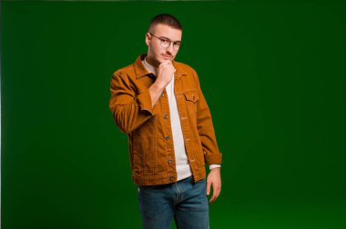 Genç yakışıklı adam ciddi görünüyor, kafası karışık, kararsız ve düşünceli, seçenekler arasında şüpheci ya da düz arkaplan karşısında seçenekler