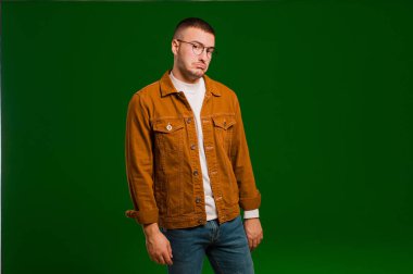 Genç ve yakışıklı bir adam kafası karışık ve kuşkulu, merak ediyor ya da düz arkaplan karşısında karar vermeye çalışıyor.