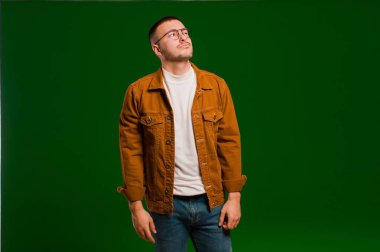 Kafası karışmış, kafası karışmış, bir sorunu çözmeye çalışan ya da düz arkaplan dışında düşünen genç yakışıklı bir adam.