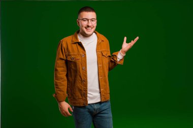 Genç yakışıklı adam kendini mutlu, şaşırmış ve neşeli hissediyor. Pozitif bir tavırla gülümsüyor. Düz zemine karşı bir çözüm ya da fikir buluyor.