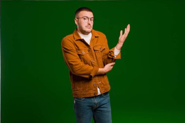 Genç ve yakışıklı bir adam kafası karışık ve bilgisiz, şüpheli bir açıklamayı merak ediyor ya da düz arkaplan hakkında düşünüyor.