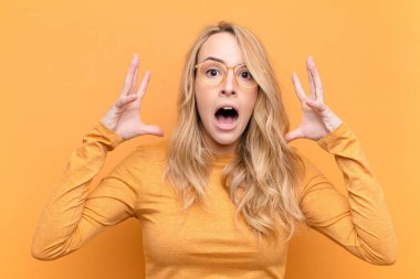 Genç, güzel, sarışın bir kadın ellerini havaya kaldırarak bağırıyor. Öfkeli, sinirli, stresli ve üzgün hissediyor.